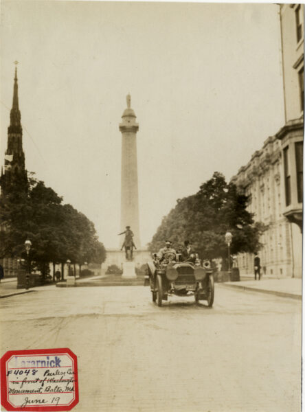 View of motorists in 1907 Peerless car in front of Washington Monument in Baltimore, Maryland. Label on front: "Lazarnick. F4048. Peerless car in front of Washington Monument, Balto., Md. June 19." Stamped on back: "Photo by N. Lazarnick, 29 West 42nd Street, New York." Handwritten on back: "Peerless, 1907. Peerless car in front of Washington Monument, Baltimore. Wednesday, June 19."